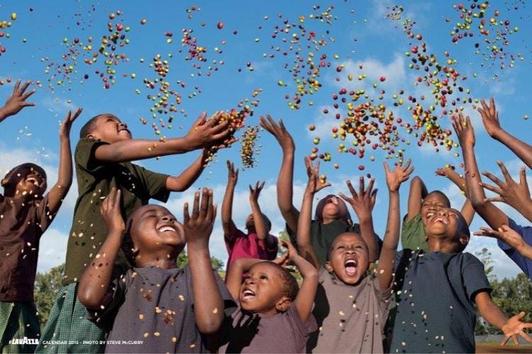 Future in Our Hands: uno degli scatti del Calendario Lavazza 2015 di Steve McCurry che ritrae i bambini della comunità di Kirua in Tanzania che gioiosi gettano al vento colorati semi di caffè